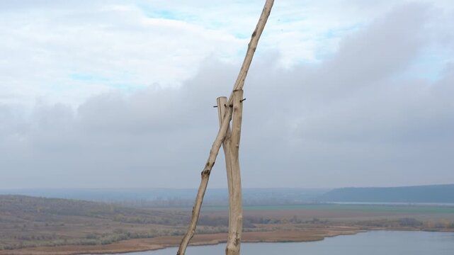 Wooden totem pole overlooking a river valley landscape. Serene panoramic view slowly revealing a vast river valley from behind a rustic wooden totem pole on a grassy hill