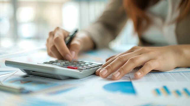 Person Calculating Finances with Calculator and Documents on Wooden Desk in Soft Light