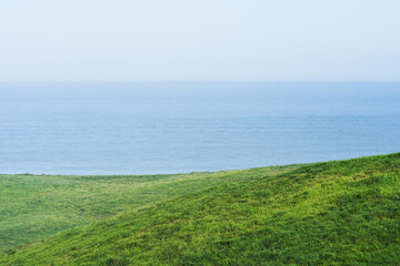 Fototapeta premium Green Coastal Hills Overlooking Calm Blue Sea Horizon