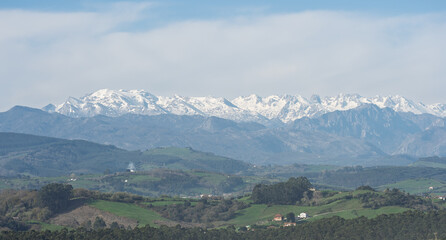 Fototapeta premium Snow Capped Mountain Range Above Green Countryside