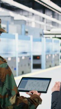 Vertical video Microelectronics factory technician and soldier analyze EDA software schematics to increase microchips production. Government looking to upgrade national semiconductors manufacturing