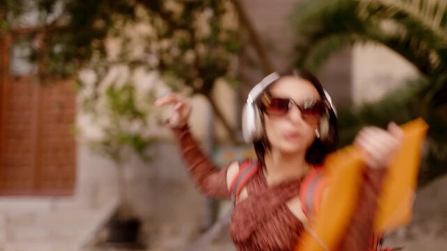Happy young woman dancing listening to music on the street