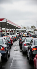 Obraz premium Long queue of passenger cars waiting for refueling at gas station during fuel crisis. Drivers in line for gasoline or diesel. Supply disruption and energy shortage, panic buying concept.