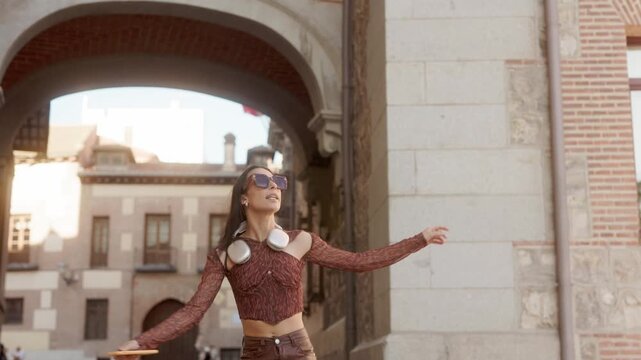 Happy energetic young woman dancing in a european city street