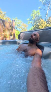Man relaxing alone in outdoor hot tub taking a selfie