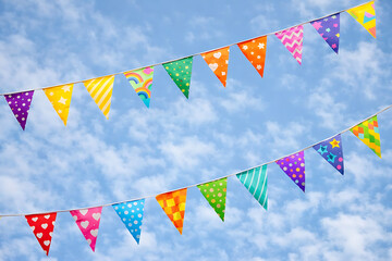 Obraz premium Colorful triangular flags on a string against a cloudy sky