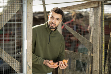 Man holding fresh eggs in a chicken coop © JackF
