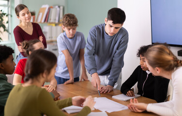 At round table meeting, teen participants discuss problem and try to find solution, teacher...