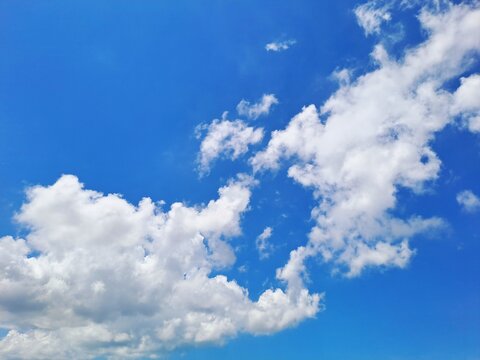 Stunning vibrant blue sky with fluffy white cumulus clouds on a bright sunny day. This high-quality nature photography captures a clear atmosphere and beautiful cloud formations, perfect for summer bg