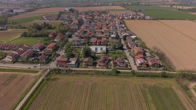 Aerial View of a Serene Village: An idyllic village nestles amidst fertile farmland, its red-tiled roofs and central church creating a picturesque rural landscape.