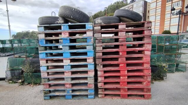 Stacks of colorful blue and red wooden pallets at a fishing harbor