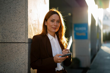 Confident businesswoman holding tablet smartphone looking at camera