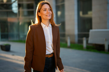 Smiling business professional walking urban street during sunset