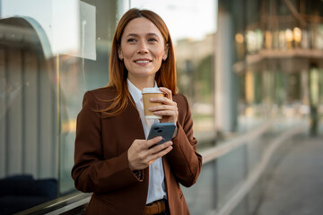 Businesswoman smiling holding smartphone and coffee cup