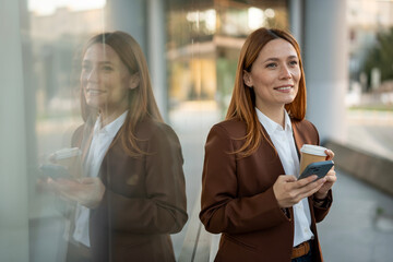 Businesswoman standing outdoors reflecting on modern building glass