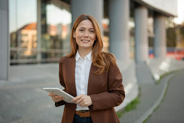 Professional woman smiling holding digital tablet outdoors