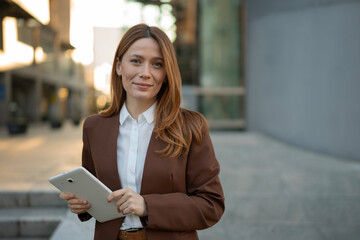 Confident businesswoman smiling while holding a digital tablet