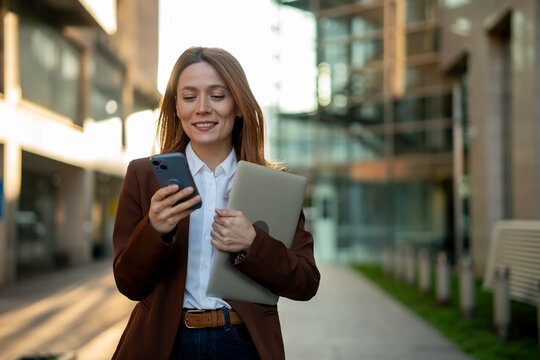 Professional woman walking and using smartphone in city