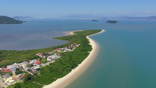 Sandy peninsula of Praia da Daniela surrounded by calm emerald waters, Florianopolis, Brazil.