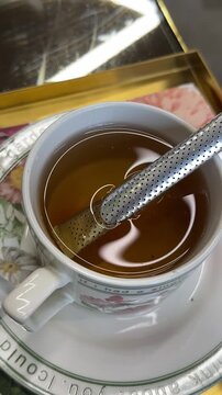 Reusable tea strainer in a cup. Vertical. Tea bag in the form of a strainer. Tea stick