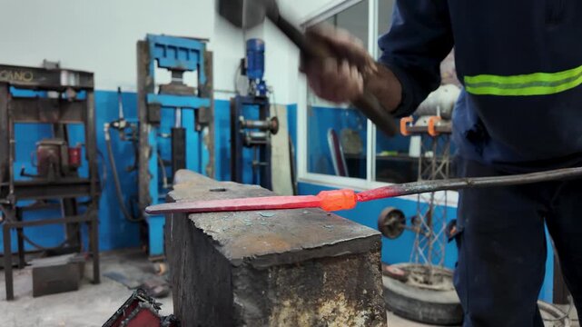 Artisan blacksmith forging a custom knife blade with a hammer and anvil in a traditional workshop.