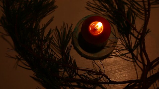 Burning Christmas wax candle on candlestick near natural dried orange on table with green natural fir branch. Home cozy aromatherapy relax eco ornament. Closeup New Year holiday. High top view angle