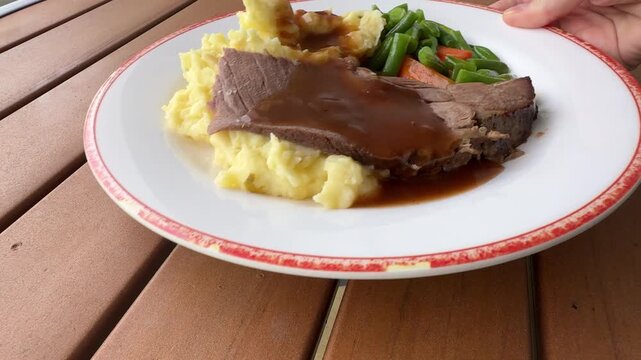Serving a Plate of Roast Beef and Mashed Potatoes with Vegetables