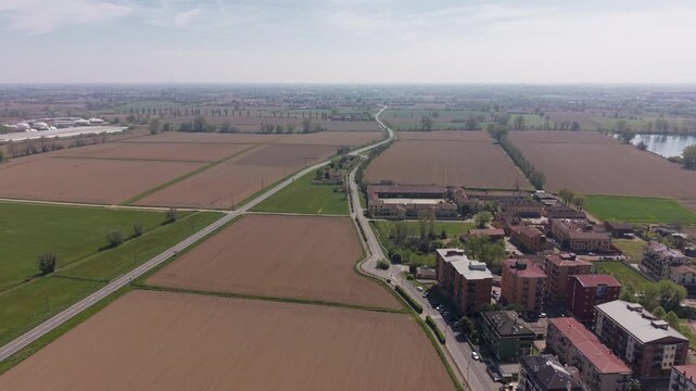 Aerial Overview of Rural Landscape: Expansive fields, roads, and buildings stretch across a tranquil rural landscape, bathed in soft, natural light, offering a sense of openness and tranquility.