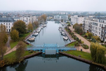 Obraz premium Boats and Buildings Along Canal, Cloudy Day, Aerial View.