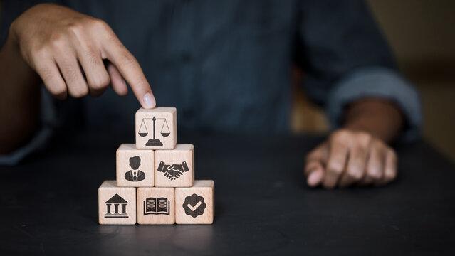 Businessman pointing at wooden blocks with justice scales and legal icons for corporate governance.