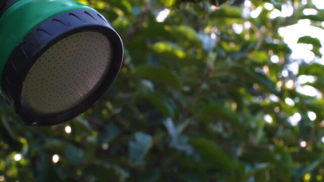 High-detail slow motion b-roll footage of an outdoor shower or garden sprayer being activated with water droplets spraying out