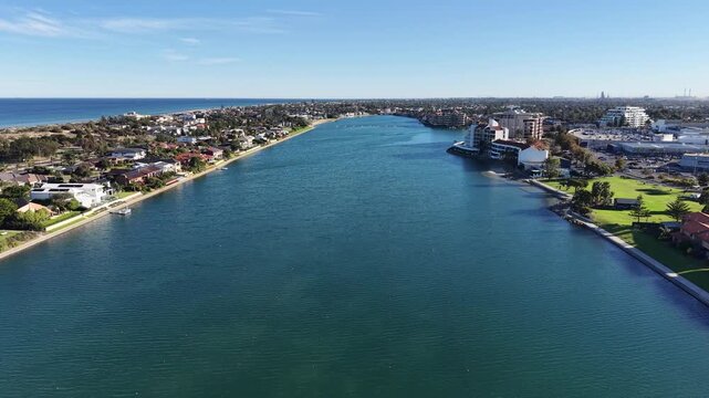 High altitude aerial drone shot of a beautiful coastal town with blue river water and residential architecture.