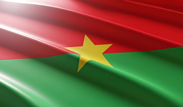 Close-up view of the national flag of Burkina Faso waving with a vibrant red and green design and a prominent yellow star in the center, illuminated by a soft light.