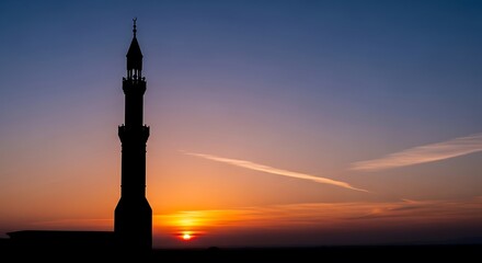 Obraz premium Silhouette of a majestic mosque tower against a vibrant sunset scene