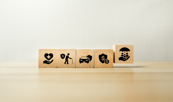 Insurance coverage and financial protection planning concept with wooden blocks showing health, life, car, and finance icons, with family protection symbol representing risk management, security