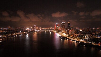 Fototapeta premium Da Nang City, Vietnam: 4K aerial drone footage of night skyline, illuminated bridges, riverfront, city lights, urban landscape and waterfront reflections. 