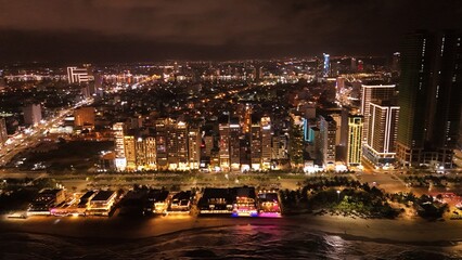 Obraz premium Da Nang City, Vietnam: 4K aerial drone footage of night skyline, illuminated bridges, riverfront, city lights, urban landscape and waterfront reflections. 