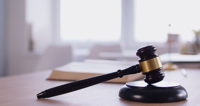 Dark brown wooden gavel and sounding block lying on desk in judge office. Legal symbol of justice and law authority, representing court decisions, legal proceedings and power of judiciary system.