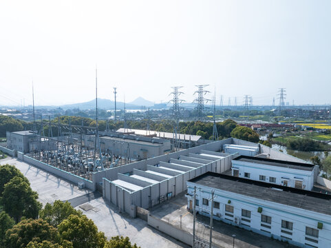 Aerial view of substation with high voltage equipment and transmission towers under clear sky