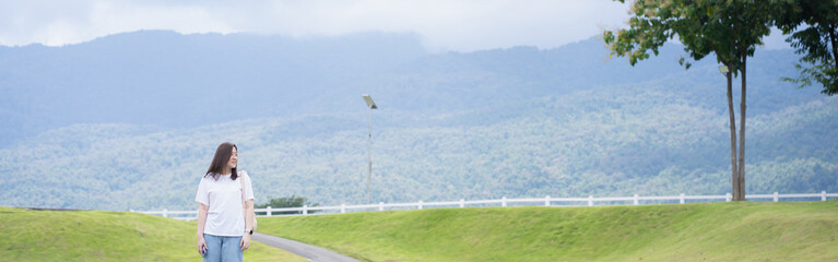 Fototapeta premium Relax and wellness concept with woman walk on road in garden and mountain background at chiangmai thailand in raining season