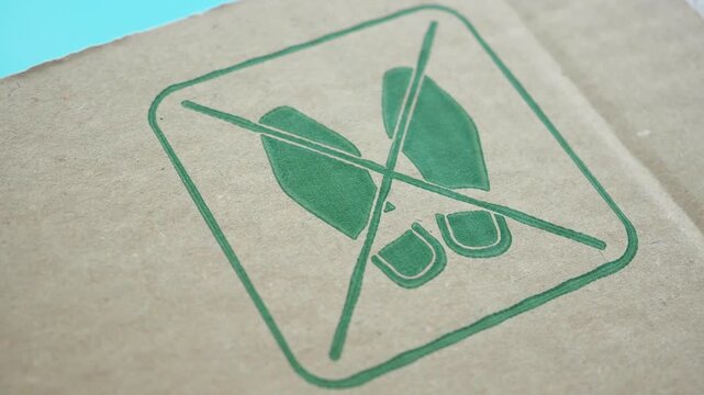 Close up view of the green do not step symbol on brown cardboard box surface.