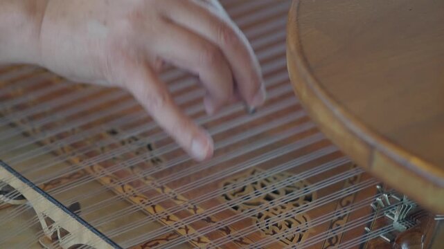 Musician playing traditional plucked string instrument kanun in slow motion close-up footage.