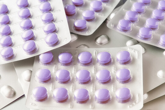 A vibrant close-up of purple medicine pills neatly sealed in bli
