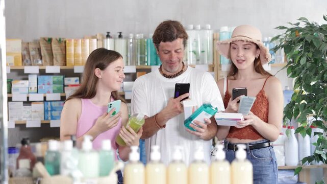 Man with wife and teen daughter in pharmacy scans QR code on drug store assortment items. Client uses link to go to manufacturers website. 