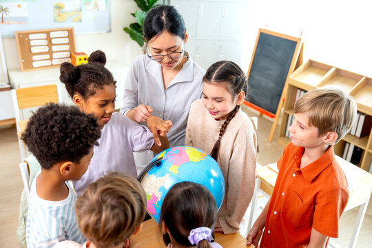 High view of teacher give the question about country on earth and tell the kids point on model globe and they look enjoy and fun with this activity.