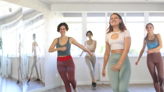 Positive incendiary female teacher conducts modern dance lessons for group of girls. Active hobby, movement, learning modern dynamic dances