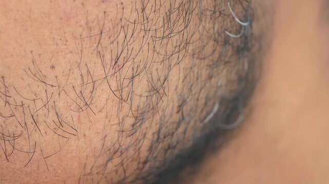 Close up view of mans finger touching coarse beard hair and skin in slow motion cinematic.
