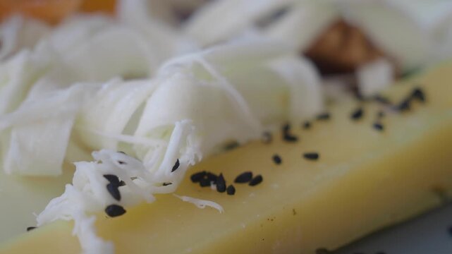 Fresh cheese platter with black sesame seeds and walnuts macro shot showing food textures.