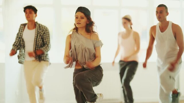 Young man standing performs basic hip hop movements in front of group of students. Developing precise movements, rehearsing arc elements, nae nae moving 