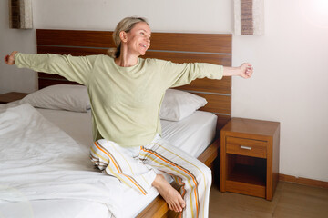 Happy Refreshed Woman waking up from Bed in the Morning by Stretching hand © Tatyana Gladskih